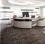 موكيت للمكاتب مصمم خصيصًا للمكاتب على شكل بلاطات مربعة، ويتميز بنمط خطوط رأسية متدرجة بدرجات اللون الرمادي والبيج،